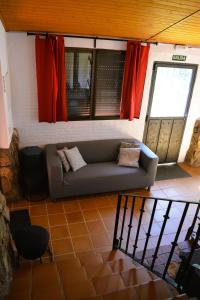 a living room with a couch and red curtains at Casa Rural Las Gesillas in Arenas de San Pedro