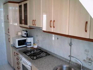 a kitchen with a stove and a microwave at Apartamentos Playa Monte Pindo - Lobeira do Mar in O Pindo