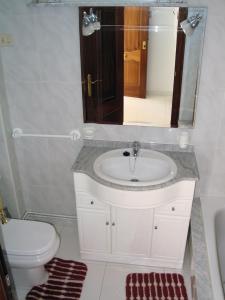 a bathroom with a sink and a toilet and a mirror at Apartamentos Playa Monte Pindo - Lobeira do Mar in O Pindo +31 photos