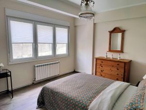 a bedroom with a bed and a dresser and windows at Apartamentos Playa Monte Pindo - Morada do Camiño in Cee