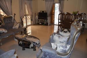 a living room with chairs and a couch and a tv at VICTOR & VICTORY GUEST HOUSE DAMAS-RAIL OBOBOGO Source in Yaoundé