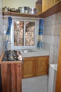 a kitchen with a stove and a window at VICTOR & VICTORY GUEST HOUSE DAMAS-RAIL OBOBOGO Source in Yaoundé +26 photos