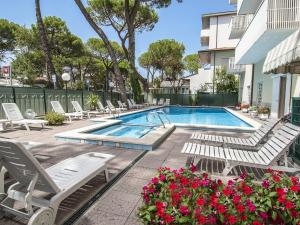 a swimming pool with lounge chairs and flowers at Hotel Vela in Milano Marittima