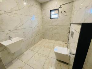a white bathroom with a sink and a toilet at Blue Lagoon Inn Resort in Hosa Kannambādi