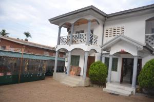 a white building with a balcony on top of it at VICTOR & VICTORY GUEST HOUSE DAMAS-RAIL OBOBOGO Source in Yaoundé