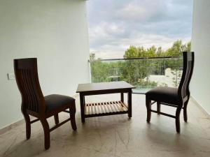 two chairs and a table in a room with a window at Blue Lagoon Inn Resort in Hosa Kannambādi