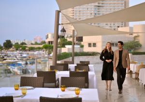 a man and a woman walking on a patio at a restaurant at InterContinental Abu Dhabi by IHG in Abu Dhabi