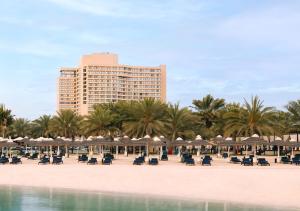 a beach with chairs and umbrellas and a building at InterContinental Abu Dhabi by IHG in Abu Dhabi
