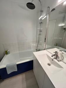 a white bathroom with a sink and a shower at La Coquille - Coquet T2 à 200m Juno Beach & Plage in Courseulles-sur-Mer