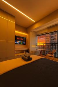 a bedroom with a bed with a television and a balcony at Studio 1106 Raizes Tucuruvi- Proximo ao shopping in Sao Paulo