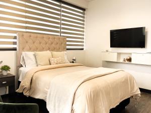 a bedroom with a large bed with a flat screen tv at Sky Suites - Amazing Location in La Paz