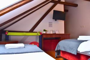 ein Schlafzimmer mit zwei Betten, einem Schreibtisch und einem Fernseher in der Unterkunft Sobe Bimbo in Zaprešić