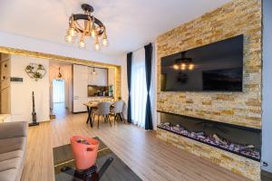 a living room with a fireplace with a tv on a brick wall at Ama Garden Spa Apartment Busteni in Buşteni +66 photos