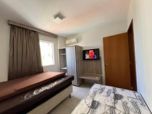 a small bedroom with a bed and a television at Privé Riviera Park Apt 730 in Caldas Novas