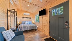 a bedroom with a bed and a tv and a door at Mountain Haven: Cozy Tiny Home on 16 Acres in Jonathan