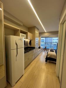 a kitchen with a white refrigerator and a large window at Studio 1106 Raizes Tucuruvi- Proximo ao shopping in Sao Paulo