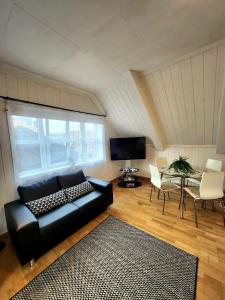 a living room with a black leather couch and a table at Dali City Senter Ap 2 in Stavanger +15 photos