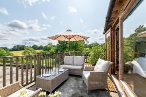 a patio with two chairs and an umbrella at Dairy Cottage in Wadhurst