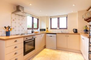 a large kitchen with white cabinets and windows at Dairy Cottage in Wadhurst