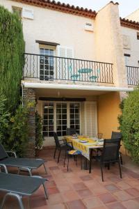 耶尔Maison Les Lauriers Roses vue sur le maquis de Porquerolles的房屋前设有带桌椅的天井。