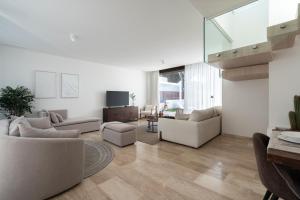 a living room with white furniture and a staircase at Casa Aura in Novo Sancti Petri
