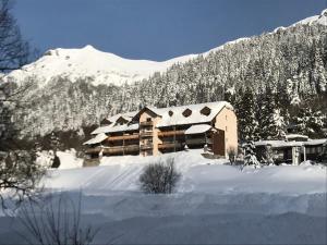 a building covered in snow in front of a mountain at ALTURA T2 Duplex wifi au pied des montagnes in Le Lioran
