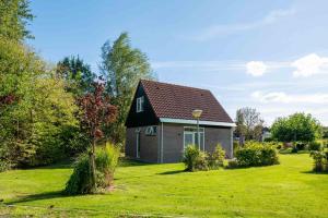 a house with a black roof on a green yard at De Rakken in Woudsend