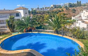 a large blue swimming pool with palm trees and buildings at 3 Bedroom Cozy Home In Fuengirola in Torremuelle