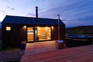 a small cabin with a deck and a tub at NestOff in Romhány +8 photos