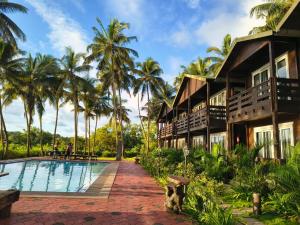 a resort with a swimming pool and palm trees at Seclude Eco Cottages in Anjuna