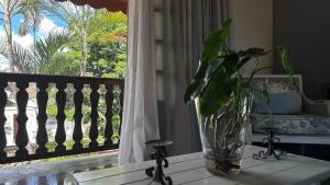 a vase sitting on a table next to a window at Recanto Amana – Casa Completa no Centro de SJBV in São João da Boa Vista