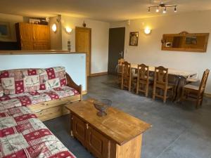 uma sala de estar com um sofá, uma mesa e cadeiras em Rocher du Cerf skis aux pieds 3 ch 2 sdb em Le Lioran