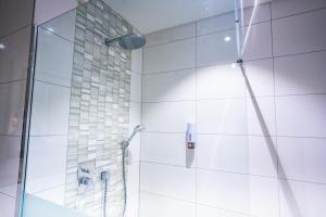 a bathroom with a shower with a glass door at Puzzle Hotel Airport Frankfurt in Rüsselsheim +30 photos