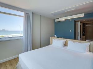 a bedroom with a large bed with a large window at Mercure Rio de Janeiro Barra da Tijuca in Rio de Janeiro +76 photos