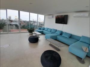ein Wohnzimmer mit einer blauen Couch und einem großen Fenster in der Unterkunft DEPARTAMENTO EN EQUIPETROL CON PISCINA ATEMPERADA- GYM Y PARQUEO GRATIS, CERCA DEL VENTURA MALL , LOS TAJIBOS, MANZANA 40 y SUPERMERCADOS in Santa Cruz de la Sierra