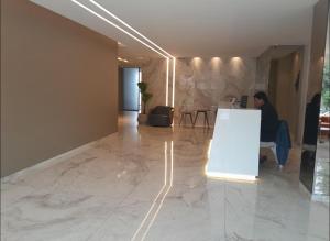 ein Mann sitzt an einer Theke in einem Raum mit Marmorboden in der Unterkunft DEPARTAMENTO EN EQUIPETROL CON PISCINA ATEMPERADA- GYM Y PARQUEO GRATIS, CERCA DEL VENTURA MALL , LOS TAJIBOS, MANZANA 40 y SUPERMERCADOS in Santa Cruz de la Sierra + 60 Fotos