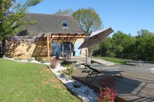 a wooden deck with an umbrella and benches at Les Combes avec piscine chauffée au nord Sarlat in LʼAir