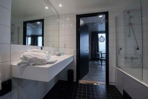 a bathroom with a sink and a tub and a mirror at Scandic Sortland in Sortland +126 photos