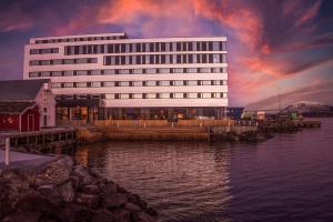 a large white building next to a body of water at Scandic Sortland in Sortland