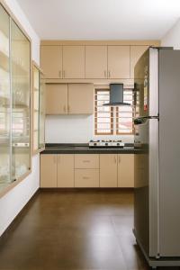 a kitchen with white cabinets and a stainless steel refrigerator at Tranquil Gudalur Stay Surrounded by Tea & Forests in Gūdalūr