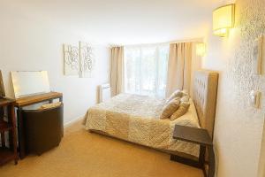 ein kleines Schlafzimmer mit einem Bett und einem Fenster in der Unterkunft Le Clos du Roc d'Azur Suite climatisée , terrasses privées, piscine, parking sécurisé in Roquefort-les-Pins + 7 Fotos