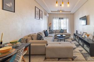 ein Wohnzimmer mit Sofa und Tisch in der Unterkunft Studio chic et paisible avec piscine parc et plage in Aïn Harrouda