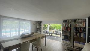 ein Wohnzimmer mit einem Tisch, Stühlen und einem Bücherregal in der Unterkunft Le Clos du Roc d'Azur Suite climatisée , terrasses privées, piscine, parking sécurisé in Roquefort-les-Pins