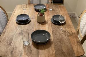 a wooden table with black plates and wine glasses at Sleeps 11 -Pets Ok - Private Garden - Free Parking in Dagenham Dock