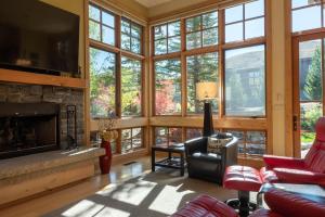 een woonkamer met een open haard en grote ramen bij Angani Way Townhome 104 in Elkhorn Village
