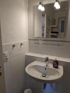 a white bathroom with a sink and a mirror at Apartment Familie Scheibel in Bad Vilbel +8 photos