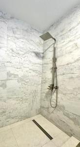 a shower in a bathroom with white marble walls at City Apartments in Ivano-Frankivsʼk