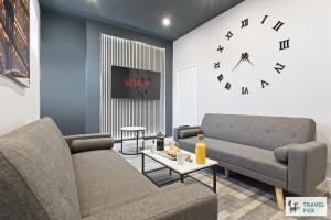 a living room with a couch and a clock on the wall at Bella's House 12mins bus to Motor Point Arena Free Street Parking in Nottingham