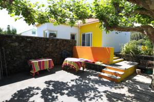 een achtertuin met een tafel en stoelen en een muur bij Casa dos Biscoitos in Praia da Vitória