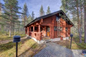 a log cabin in the woods with a wooden deck at Laavu 13 Original Log Cabin with Sauna in Pyhätunturi